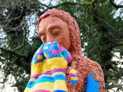 A sculpture of a dark haired woman hugging a rainbow coloured baby.